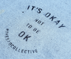 The words "It's okay not to be ok - #thesadcollective" on a light blue background