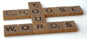 Scrabble tiles interlocking to spell "Choose Your Words"