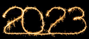 The year 2023 written in gold sparkler on a black background.