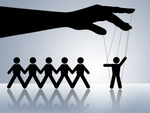 Graphic, in black on a blue gradient background, of a hand manipulating one of five stick figures with puppet strings.