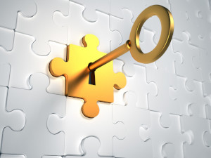 Graphic of a gold key inserted in a gold lock in the shape of a puzzle piece on a background of interlocking white puzzle pieces.