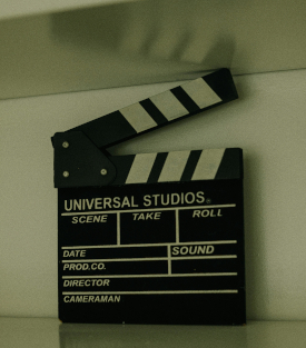 Semi-grayscale photo of a movie clapboard against a plain background.